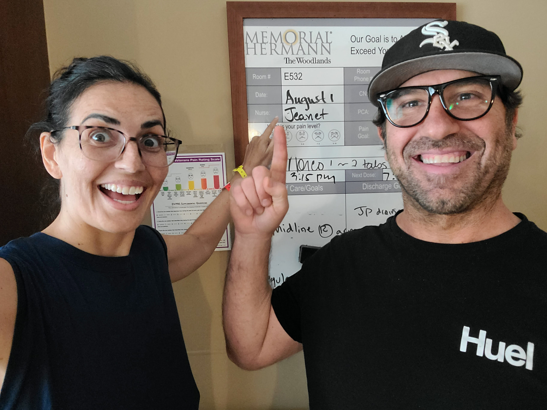 Toni and her husband pointing at the hospital room whiteboard
