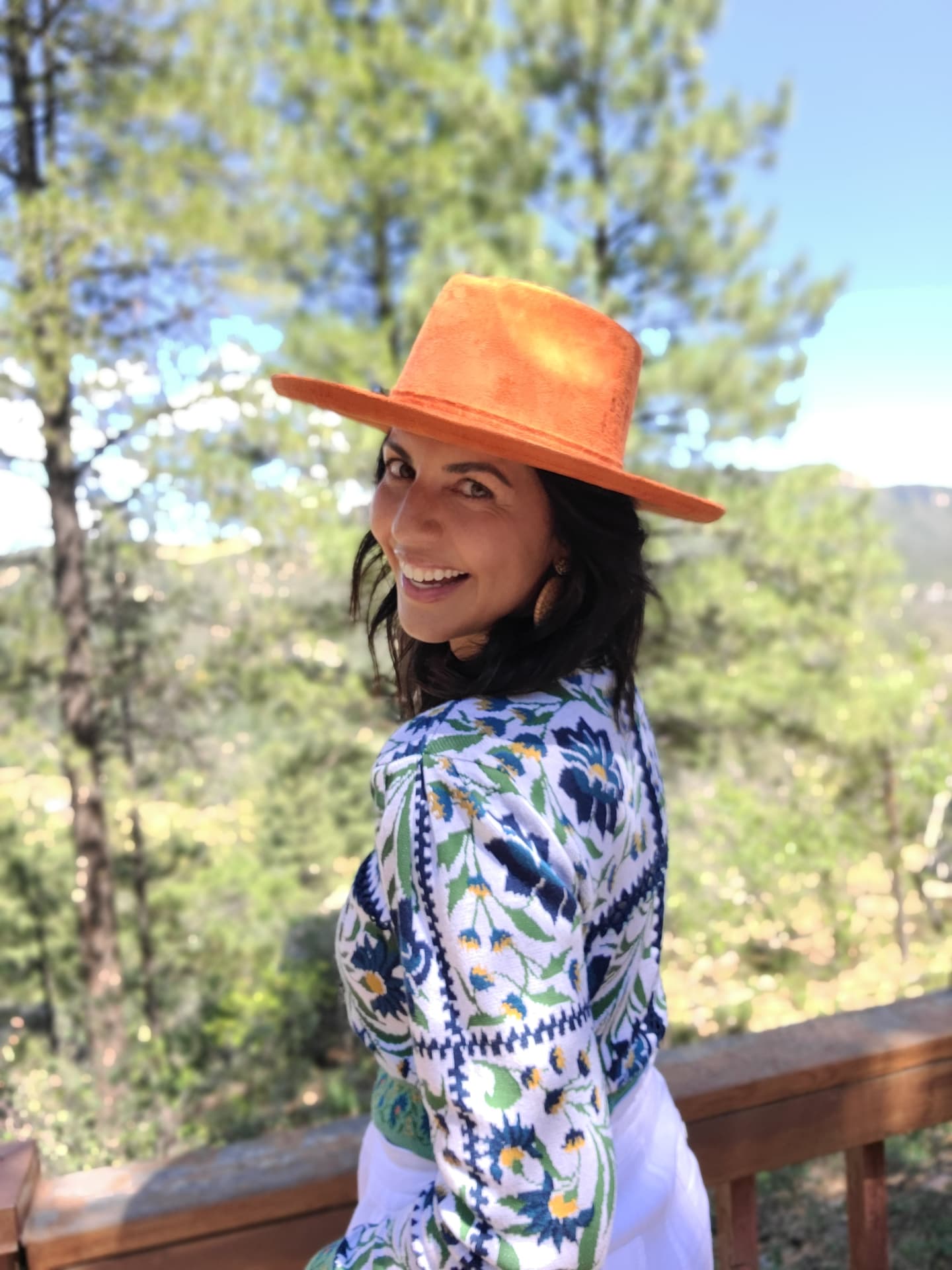 Toni in an orange hat and embroidered jacket in the pines