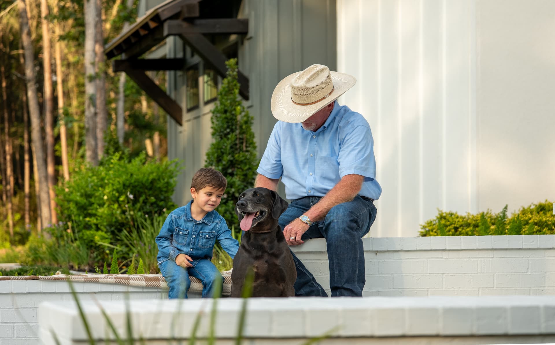 Lifestyle shoot photo of a grandfather and grandson with their dog on the porch of their new home, directed and produced by Toni Bubb for Patten Properties