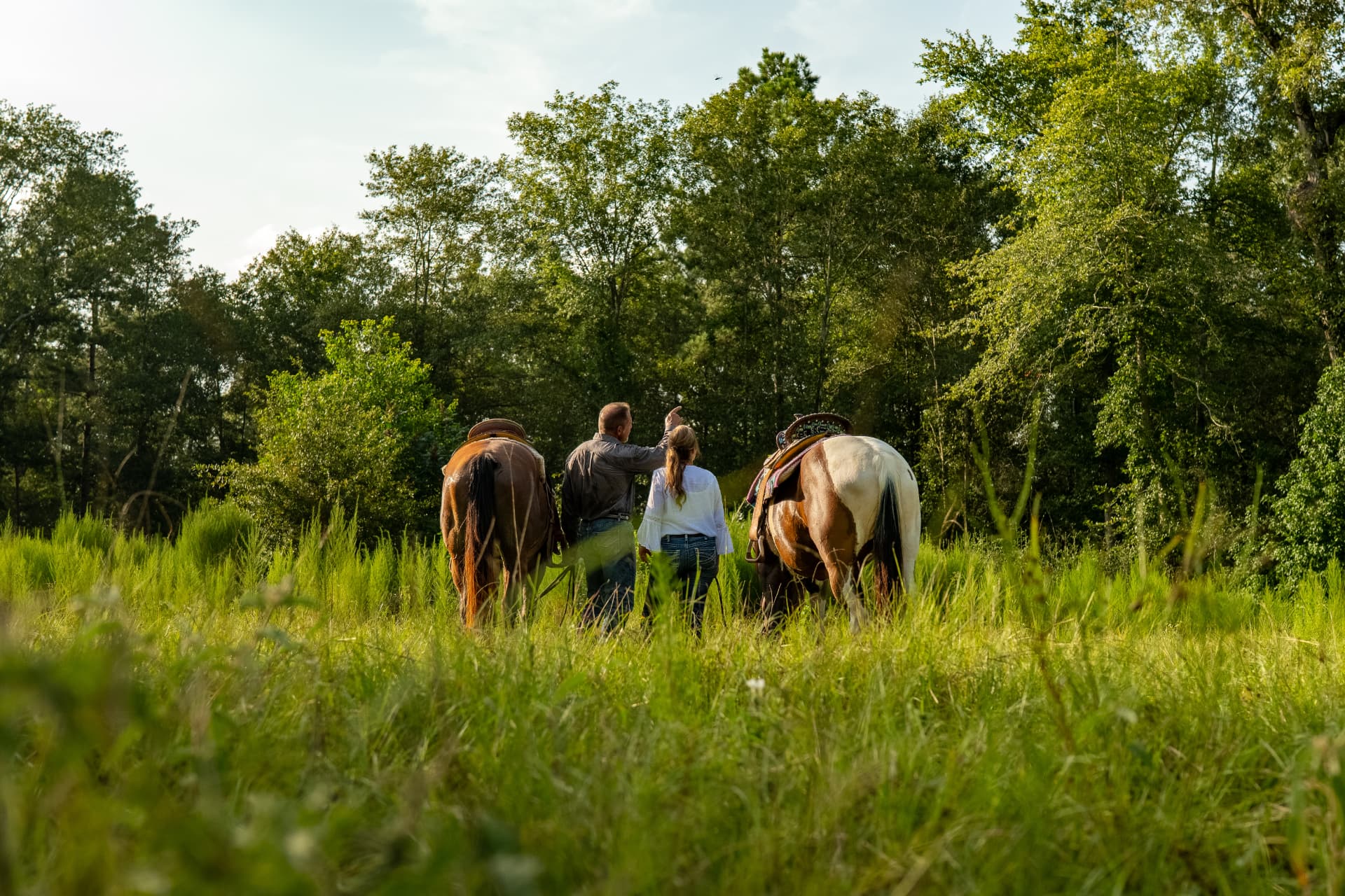 Lifestyle shoot photo of a couple walking their horses through a green meadow, directed and produced by Toni Bubb for Patten Properties